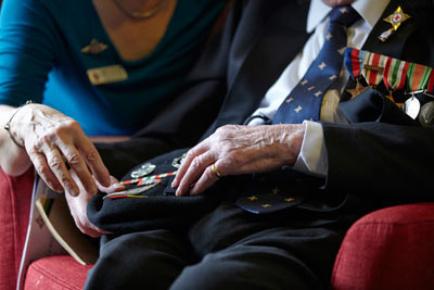 Elderly man and carer looking at military medals at RS&G care home by Janie Airey photographer