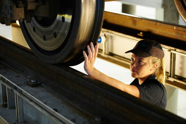 young woman inspecting train wheel in Siemens depot by Janie Airey photographer